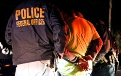 FILE-U.S. Immigration and Customs Enforcement agents surround and detain a person during a raid in Richmond, Va.