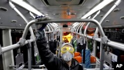 A worker disinfects a public bus against coronavirus in Tehran, Iran, in early morning of Feb. 26, 2020.