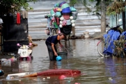 A man collects a water to clean his flooded house in Tanggerang on the outskirts of Jakarta, Indonesia, Jan. 3, 2020.