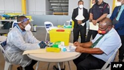 FILE - This photo taken March 30, 2021, shows Papua New Guinea's Prime Minister James Marape (R) preparing to receive a dose of the AstraZeneca COVID-19 vaccine, in Port Moresby, Papua New Guinea.