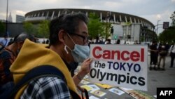 People take part in a protest against the hosting of the 2020 Tokyo Olympic Games outside the Olympic museum in Tokyo on May 9, 2021. (Photo by Philip FONG / AFP)