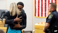 Botham Jean's younger brother Brandt Jean hugs convicted murderer and former Dallas Police Officer Amber Guyger after delivering his impact statement. She was sentenced to 10 years in jail, Oct. 2, 2019, in Dallas.