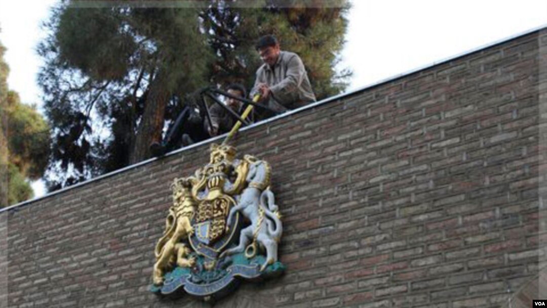 Warga Iran berusaha memindahkan lambang negara Inggris dari gedung Kedutaan Inggris di Teheran (29/11). Hubungan Inggris dan Iran tegang sejak penyerbuan Kedutaan Inggris di Teheran November lalu.