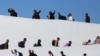 FILE - Migrants who requested an appointment for asylum in the United States walk towards El Chaparral, at the border between Mexico and the U.S, in Tijuana, Mexico Nov. 4, 2024. 