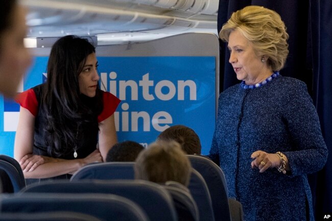 FILE - Democratic presidential candidate Hillary Clinton speaks with senior aide Huma Abedin aboard her campaign plane at Westchester County Airport in White Plains.