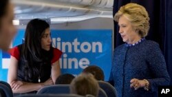 FILE - Democratic presidential candidate Hillary Clinton speaks with senior aide Huma Abedin aboard her campaign plane at Westchester County Airport in White Plains. 