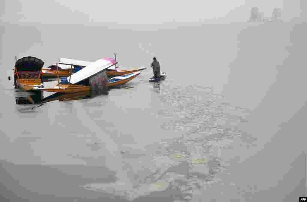A Kashmiri boatman uses his oar to break the ice layer of the frozen Dal Lake after a heavy snowfall in Srinagar.