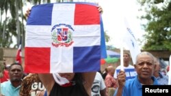 Una mujer sostiene la bandera dominicana durante una protesta en Santo Domingo, República Dominicana, el domingo 23 de febrero. 