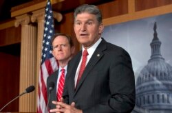 FILE - Sen. Joe Manchin, D-W.Va., right, accompanied by Sen. Patrick Toomey, R-Pa., announce that they have reached a bipartisan deal on expanding background checks to more gun buyers, April 10, 2013, on Capitol Hill in Washington.
