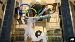 In this Oct. 28, 2013 photo, workers fix the Olympic emblem at an entrance to the railway station of Russia's Black Sea resort of Sochi.