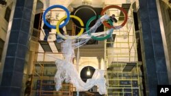 In this Oct. 28, 2013 photo, workers fix the Olympic emblem at an entrance to the railway station of Russia's Black Sea resort of Sochi.