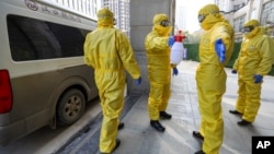 Funeral workers disinfect themselves after handling a virus victim in Wuhan in central China's Hubei Province, Thursday, Jan. 30, 2020. China counted 170 deaths from a new virus Thursday and more countries reported infections. (Chinatopix via AP)