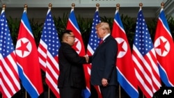 FILE - Kim Jong Un and President Donald Trump shake hands prior to their meeting in Singapore, June 12, 2018.