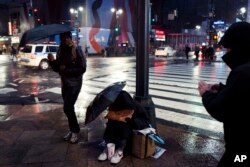 People walk by a homeless man panhandling on a New York sidewalk, Jan. 24, 2017.