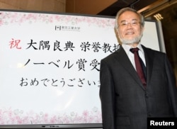 Yoshinori Ohsumi, a professor of Tokyo Institute of Technology smiles in front of a celebration message board after he won the Nobel medicine prize in Yokohama, Japan, October 3, 2016 in this photo released by Kyodo.