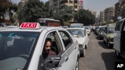 FILE - A taxi driver waits in line for fuel at a gas station in Cairo's neighboring city of Giza, Egypt, Sept. 4, 2014. Egypt's parliament approved a law to govern popular ride-hailing apps Uber and Careem, which had faced legal challenges. 