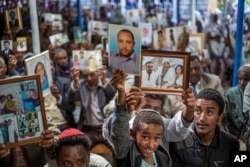 FILE - Members of Ethiopia's Jewish community hold up pictures of their relatives in Israel, during a solidarity event at a synagogue in Addis Ababa, Ethiopia, Feb. 28, 2018.