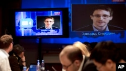 Las pantallas de televisión muestran a Edward Snowden en el momento en que hizo dos preguntas al presidente ruso Vladimir Putin.
