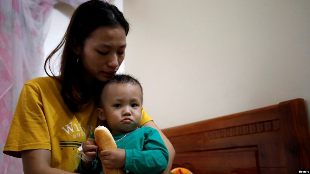 Hoang Thi Thuong menggendong putranya di provinsi Nghe An, Vietnam (foto: dok). Suaminya, Nguyen Dinh Tu, termasuk salah satu dari 39 korban tewas dalam truk di Inggris. 