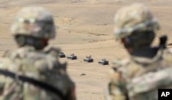 FILE - US soldiers watch as Georgian military vehicles take part in NATO-led Noble Partner 2017 multinational military exercises at the military base of Vaziani, outside Tbilisi, Georgia, Aug. 9, 2017.