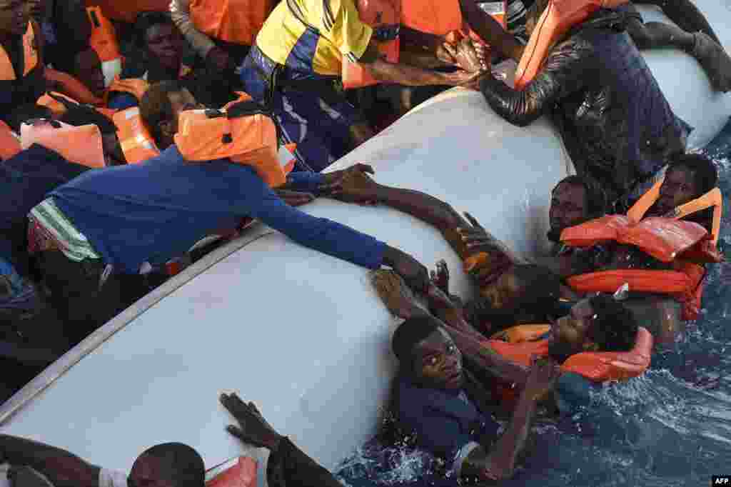 이탈리아 적십자사와 몰타 NGO가 지중해 리비아 연안에서 공동진행한 난민 구조 작업 중 난민들이 보트에 탑승하기 위해 안간힘을 쓰고있다.&nbsp; &nbsp;