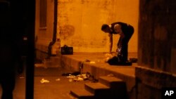 FILE - A Chicago police officer picks through debris at the crime scene where a number of people were shot in a city park on the south side of Chicago, Sept. 19, 2013.