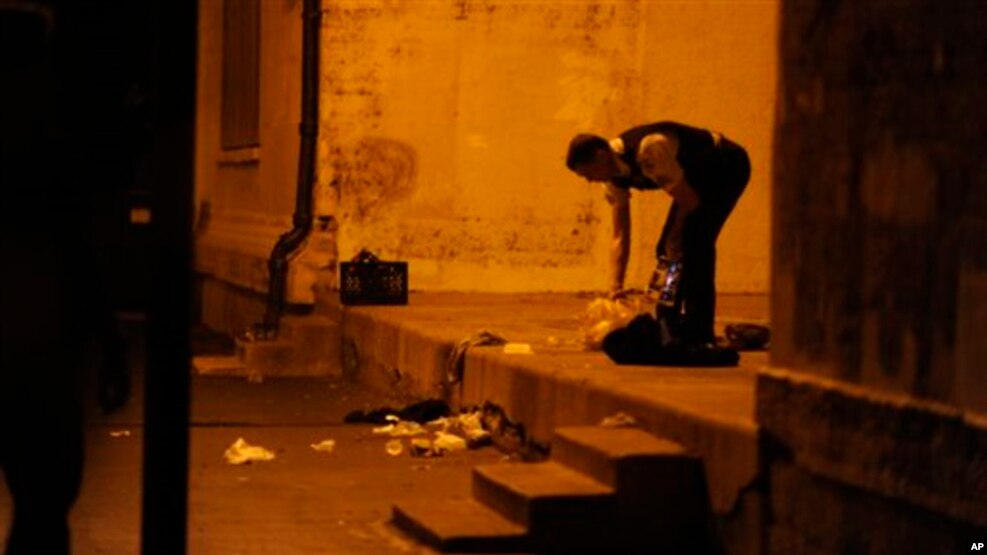 FILE - A Chicago police officer picks through debris at the crime scene where a number of people were shot in a city park on the south side of Chicago, Sept. 19, 2013.
