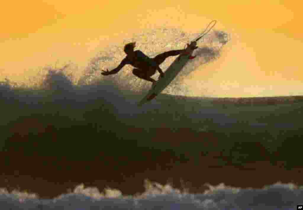 A young surfer sails his board off a wave as large swells hit the California coastline at dusk in Cardiff , California January 5, 2012. REUTERS/Mike Blake (UNITED STATES - Tags: SOCIETY ENVIRONMENT)