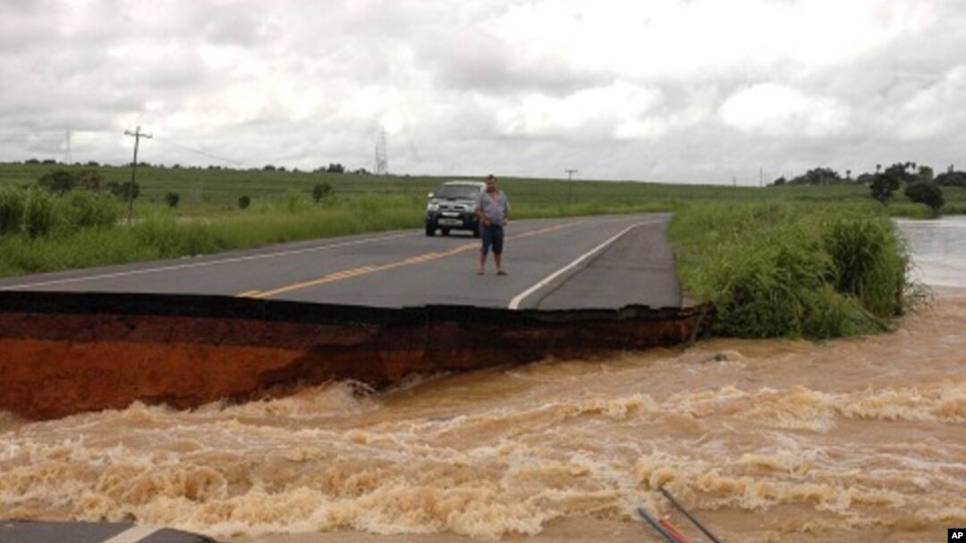 A motorist stands on the edge of a break in highway BR 356 that was washed away after several days of heavy rains swelled the Muriae River in Campos, 230 kms (142 miles) northeast of Rio de Janeiro, January 5, 2012.