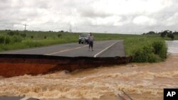 A motorist stands on the edge of a break in highway BR 356 that was washed away after several days of heavy rains swelled the Muriae River in Campos, 230 kms (142 miles) northeast of Rio de Janeiro, January 5, 2012.