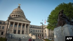 FILE - People stand next to the Confederate Mothers statue (R) outside the Mississippi State Capitol building during the state legislature's historic vote to change the Mississippi flag in Jackson, Mississippi on June 28, 2020.