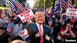 Para pendukung Presiden Donald Trump berdemo sambil membawa foto Trump untuk memprotes hasil pemilihan presiden 2020, di Atlanta, Georgia, 21 November 2020 (Foto: Reuters)