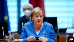 German Chancellor Angela Merkel removes her mask, at the beginning of a Federal Cabinet meeting at the Federal Chancellery, in Berlin, Sept. 8, 2021. 
