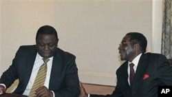 Zimbabwean President Robert Mugabe, right chats to Prime Minister Morgan Tsavangirai during their end of year press conference at State House in Harare, Dec 20, 2010