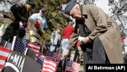 World War II veteran Robert Case, who was a captain in the US Army Air Corp., places a flag in front of a Vietnam Veterans Memorial during Veteran's Day ceremonies, Monday, Nov. 11, 2013, at Eden Park in Cincinnati. 