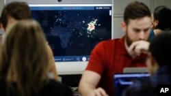 FILE - A worker at HealthMap, a system using artificial intelligence to monitor global disease outbreaks, mines health data to keep the system up to date in a work area at Boston Children's Hospital in Boston, Massachusetts, Feb. 13, 2020.