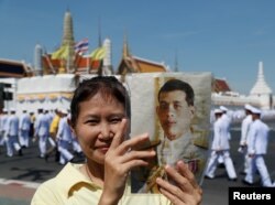 A woman holds an image of King Maha Vajiralongkorn during his coronation in Bangkok, May 4, 2019.