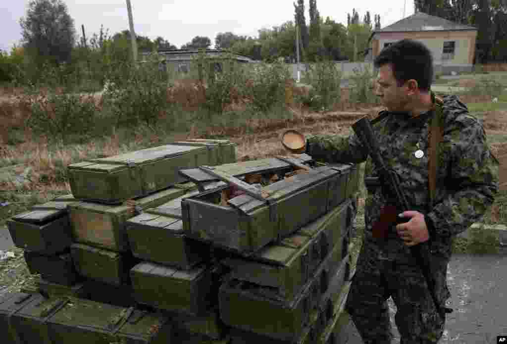 A Pro-Russian rebel inspects an abandoned Ukrainian checkpoint near the village of Nyzhnya Krynka, eastern Ukraine, Sept. 23, 2014.