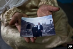 FILE - Amineh Hamad, 58, a Syrian refugee from Eastern Ghouta, shows a photograph of herself and her husband Ali Abdulqader, 58, at her shelter in the Ritsona refugee camp, Greece, Jan. 7, 2017. "It was the last time we visited the Roman site of Busra al-Sham. ...We miss these days. We hope one day it will come back," Amineh said.