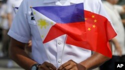 Seorang anggota Gara Pantai Filipina memegang bendera saat kunjungan persahabatan kapal Angkatan Laut China, Qi Jiguang, di pelabuhan Manila, Filipina, 14 Juni 2023. (Foto: AP)