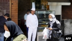 Iranians pass by a restaurant in the capital city of Tehran, on May 26, 2020. - Iran on May 25, reopened major Shiite shrines across the Islamic republic, more than two months after they were closed, as it reported its lowest deaths from coronavirus…