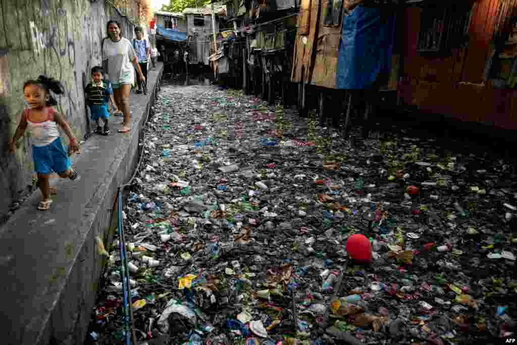 People walk along a canal polluted with plastic and garbage at the Estero de San Lazaro in Manila in the Philippines.
