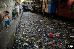 People walk along a canal polluted with plastic and garbage at the Estero de San Lazaro in Manila in the Philippines on March 22, 2019.