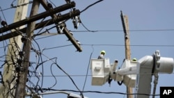 FILE - A brigade from the Puerto Rico Electric Power Authority repairs distribution lines damaged by Hurricane Maria in the Cantera community of San Juan, Puerto Rico, Oct. 19, 2017. The storm struck after the authority had filed for bankruptcy in July, put off maintenance and had finished dealing with outages from Hurricane Irma.