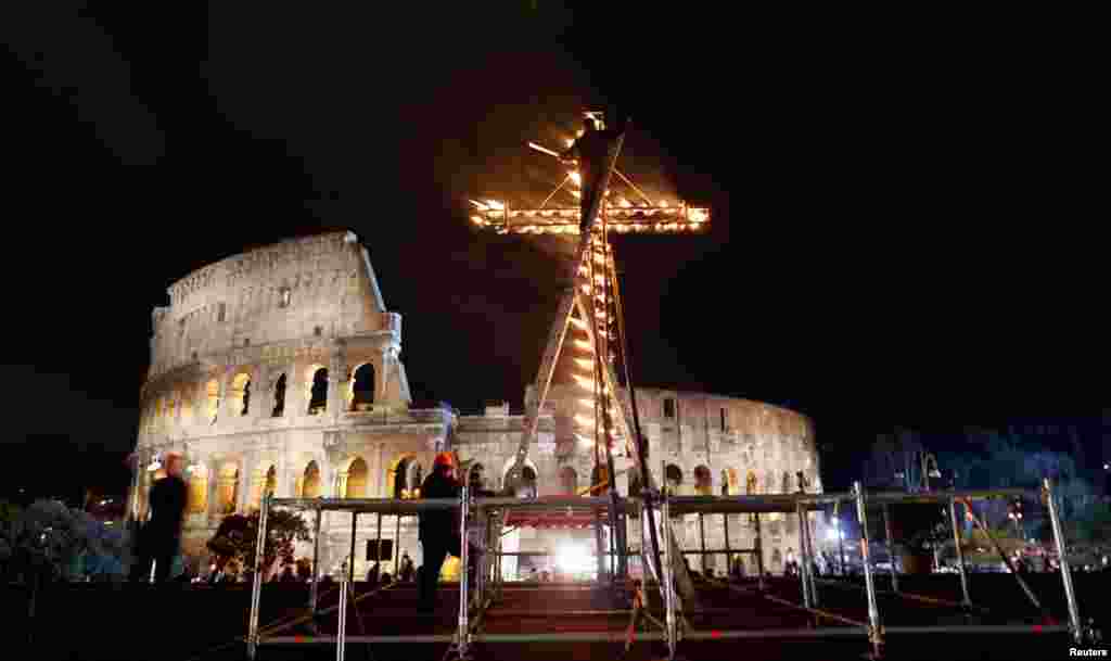 在2013年3月29日耶稣受难日的庆祝活动中，在教宗方济在罗马竞技场前带领十字架之路的游行开始前，一名工作人员点燃一个十字架。