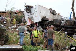 Petugas memeriksa properti yang hancur akibat angin puting beliung di Greenfield, Iowa, 21 Mei 2024. (AP/Charlie Neibergall)