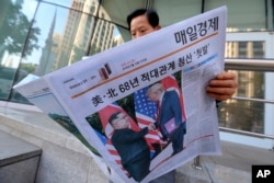 FILE - A man reads a newspaper reporting on the summit between U.S. President Donald Trump and North Korean leader Kim Jong Un, at a newspaper stand in Seoul, South Korea, June 12, 2018.