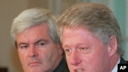 House Speaker Newt Gingrich (left) looks on as President Clinton talks to reporters in the Cabinet Room of the White House, July 29, 1996 (file photo)