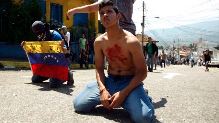 Jóvenes venezolanos de rodillas fente a la policía luego de la muerte del estudiante Kluiver Roa en San Cristóbal, el 24 de febrero.
