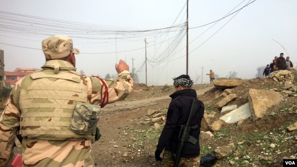 Soldados iraquíes avanzan hacia el frente de batalla mientras familias huyen en Mosul. Enero 23, 2017. (H. Murdock/VOA)